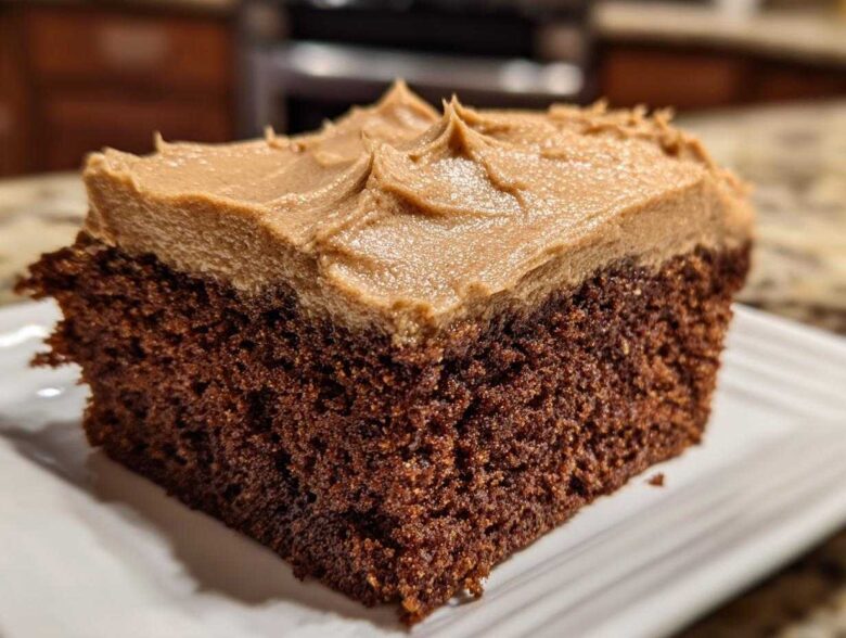 Close-up of a moist slice of dark gingerbread cake topped with thick, light brown frosting.