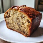 Close-up of a thick, moist slice of greek yogurt banana bread with a golden-brown crust.