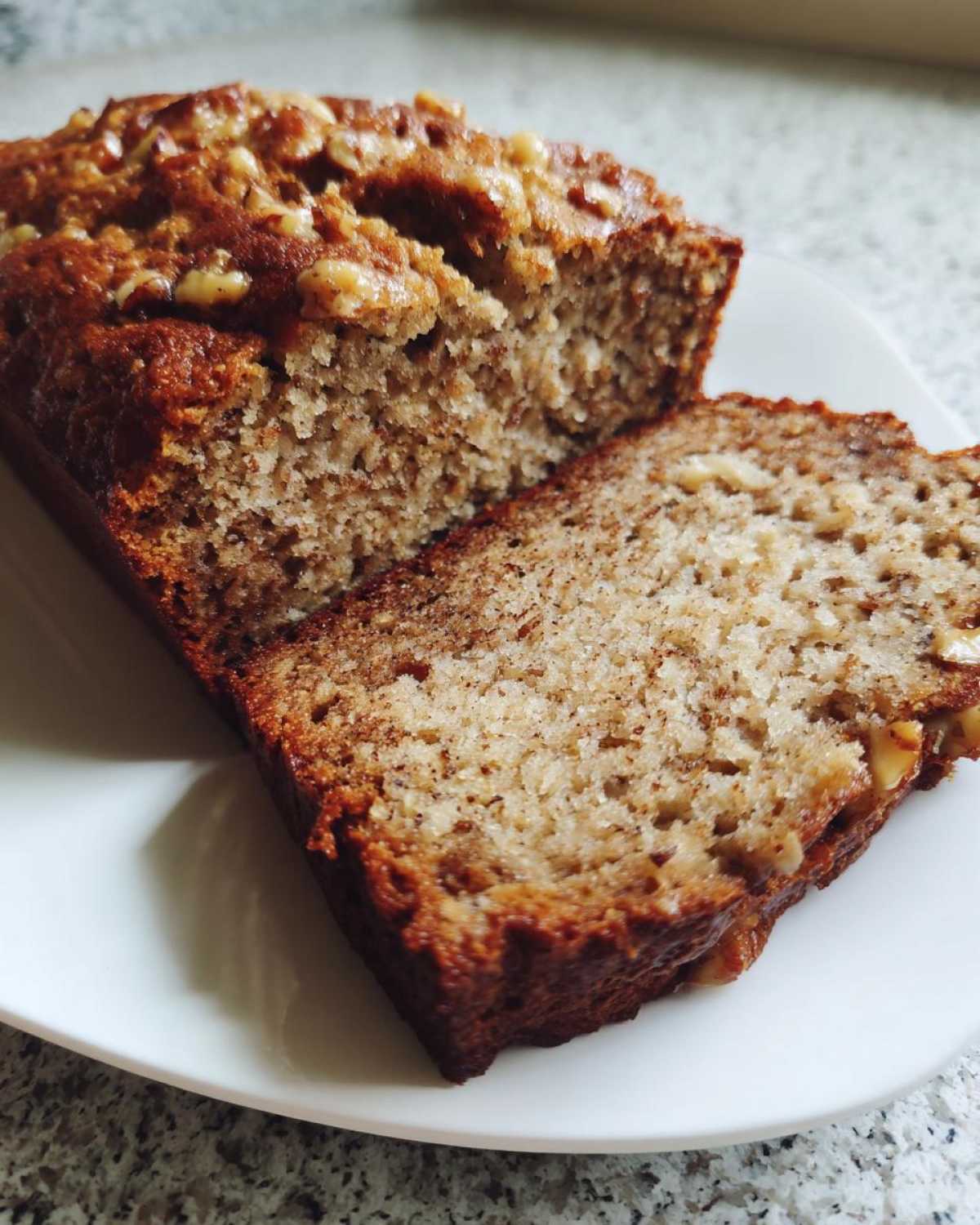 Close-up of moist sugar free banana bread, showing a slice cut from the loaf topped with walnuts.