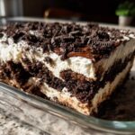 A cross-section view of a rich, layered no-bake oreo dirt cake with cream filling and chocolate cookie crumbs.