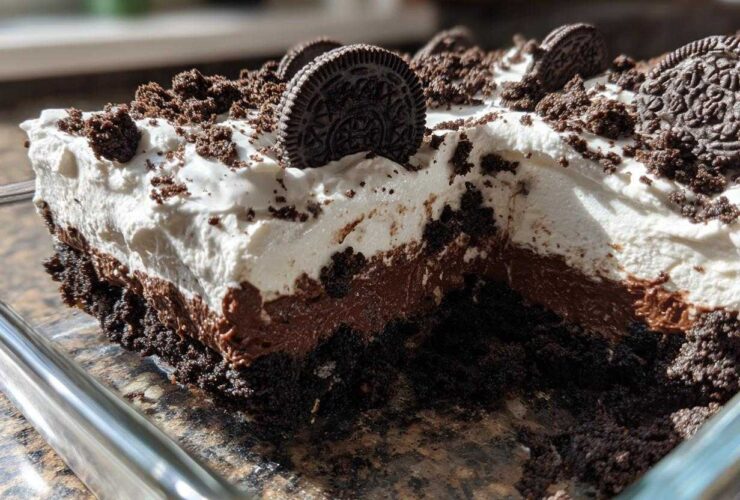 A close-up cross-section of a layered no-bake oreo dirt cake showing cookie crust, chocolate pudding, and whipped topping.