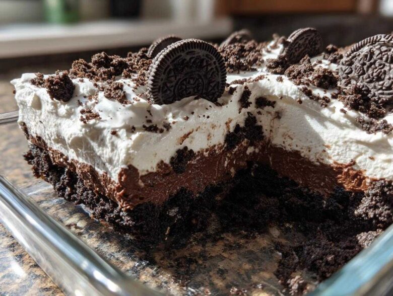 A close-up cross-section of a layered no-bake oreo dirt cake showing cookie crust, chocolate pudding, and whipped topping.