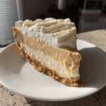 A perfect slice of no-bake peanut butter pie showing graham cracker crust, creamy peanut butter layer, and whipped topping.