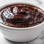 Close-up of rich, dark homemade chocolate pudding swirled in a white ceramic ramekin.