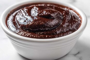 Close-up of rich, dark homemade chocolate pudding swirled in a white ceramic ramekin.