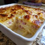 Close-up of a creamy, baked scalloped potatoes and ham casserole with a golden-brown cheesy top.