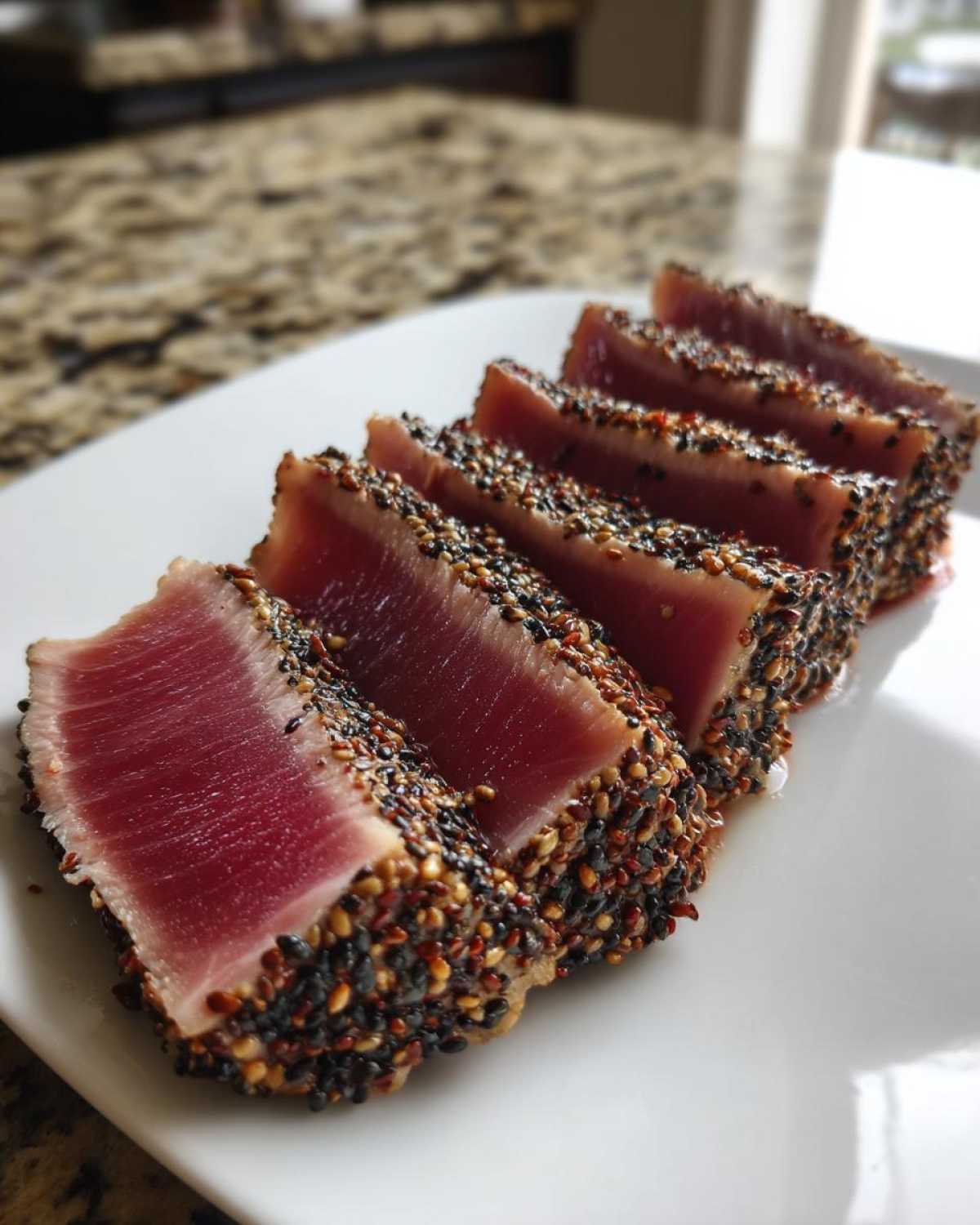 Close-up of five slices of perfectly seared ahi tuna, crusted with black and white sesame seeds.
