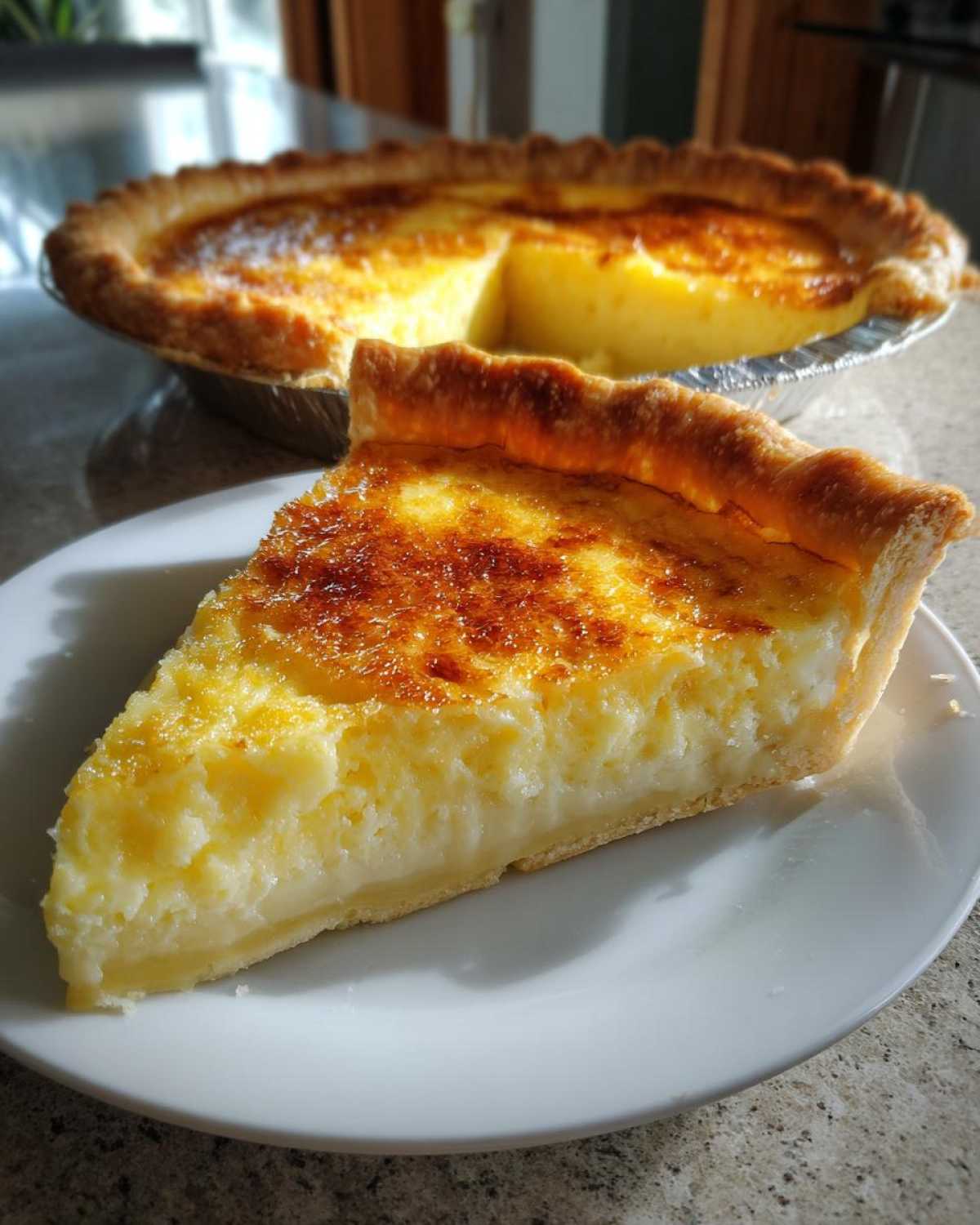 A close-up slice of creamy egg custard pie with a golden-brown top, served on a white plate.