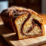 Close-up of a freshly baked loaf of pumpkin sourdough bread, showing a rich cinnamon swirl inside and a sugary crust.