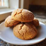 A stack of four soft, crackled applesauce cookies generously coated in granulated sugar, resting on a white plate.