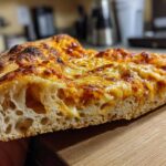 Close-up of a slice of pizza showing the airy crumb structure made from sourdough discard pizza dough.