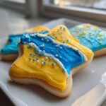 A star-shaped sugar cookie decorated with thick, bright yellow and blue sugar cookie icing and sprinkles.