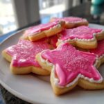 Star-shaped sugar cookies topped with bright pink icing that hardens and white sugar sprinkles.