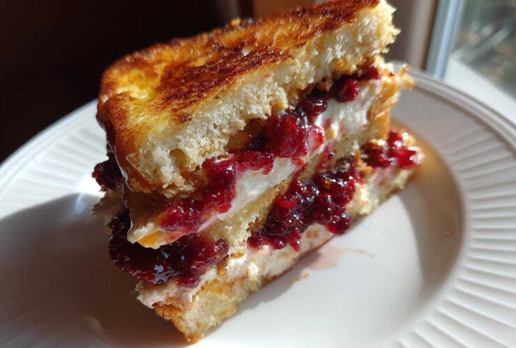 A cross-section of stuffed french toast filled with cream cheese and bright red berry jam.