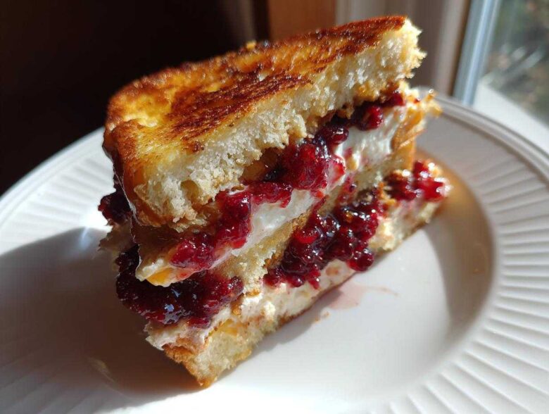 A cross-section of stuffed french toast filled with cream cheese and bright red berry jam.