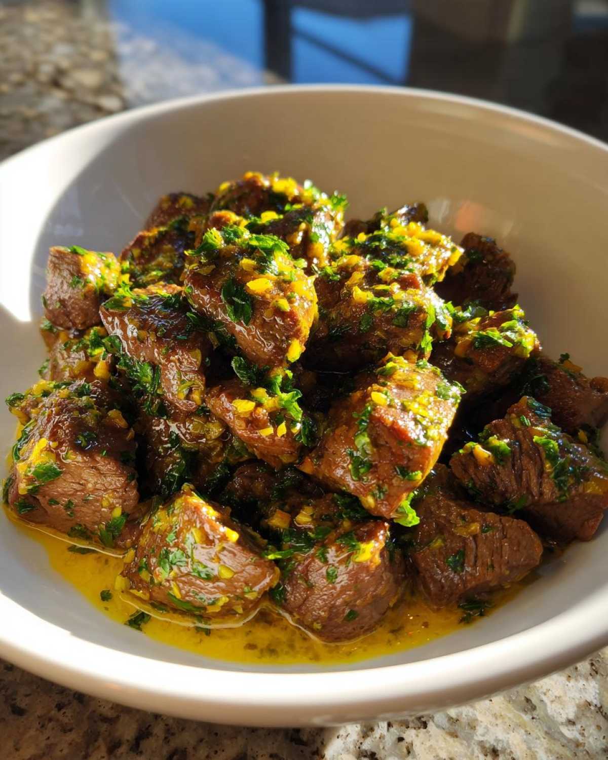 Close-up of tender crockpot steak cubes coated in a bright yellow sauce with fresh green parsley.