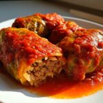 Three savory cabbage rolls stuffed with meat and rice, smothered in rich tomato sauce.