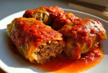 Three savory cabbage rolls stuffed with meat and rice, smothered in rich tomato sauce.