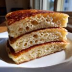 Close-up of three thick, fluffy pancakes stacked, showing the incredibly airy interior structure.