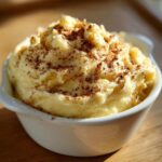 Close-up of creamy, whipped cinnamon butter sprinkled generously with ground cinnamon in a white ramekin.