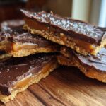 Stack of rich graham cracker toffee bars showing the crumbly base, gooey caramel, and chocolate topping sprinkled with sea salt.