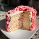 Cross-section of a three-layer rose cake showing vanilla sponge and pink filling, decorated with pink frosting roses.