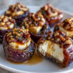 Close-up of several glistening stuffed dates filled with creamy cheese and topped with nuts and glaze, ready to serve.