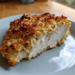 A close-up cross-section of juicy baked ranch chicken with a crispy, golden-brown topping.