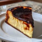 A close-up slice of creamy Basque burnt cheesecake with a dark, caramelized top.