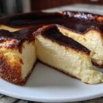 A whole Basque burnt cheesecake with two slices cut out, showing the creamy interior and dark caramelized top.