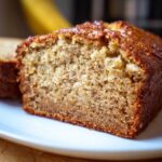 Close-up of a moist slice of the best banana bread showing its textured crumb and golden-brown crust.