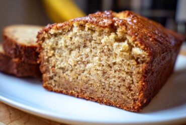 Close-up of a moist slice of the best banana bread showing its textured crumb and golden-brown crust.