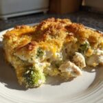 A close-up serving of creamy Chicken Divan casserole featuring chunks of chicken and broccoli under a golden, crunchy breadcrumb topping.