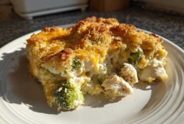 A close-up serving of creamy Chicken Divan casserole featuring chunks of chicken and broccoli under a golden, crunchy breadcrumb topping.