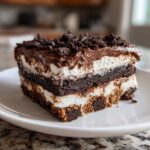 Close-up of a layered brownie refrigerator cake slice showing chocolate, cream, and crumb toppings.