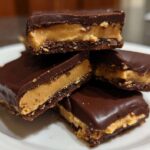 A stack of four rich, chocolate-covered Buckeye Graham Crackers showing the creamy peanut butter filling.