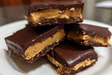 A stack of four rich, chocolate-covered Buckeye Graham Crackers showing the creamy peanut butter filling.