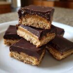 A stack of rich buckeye graham crackers bars showing the graham base, peanut butter layer, and chocolate topping.