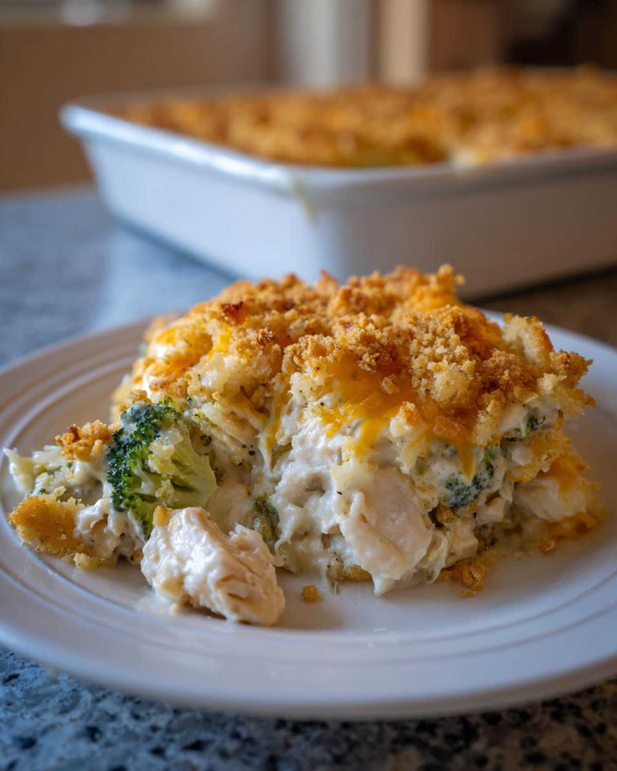 A generous serving of creamy Chicken Divan casserole topped with golden breadcrumbs and melted cheddar cheese.
