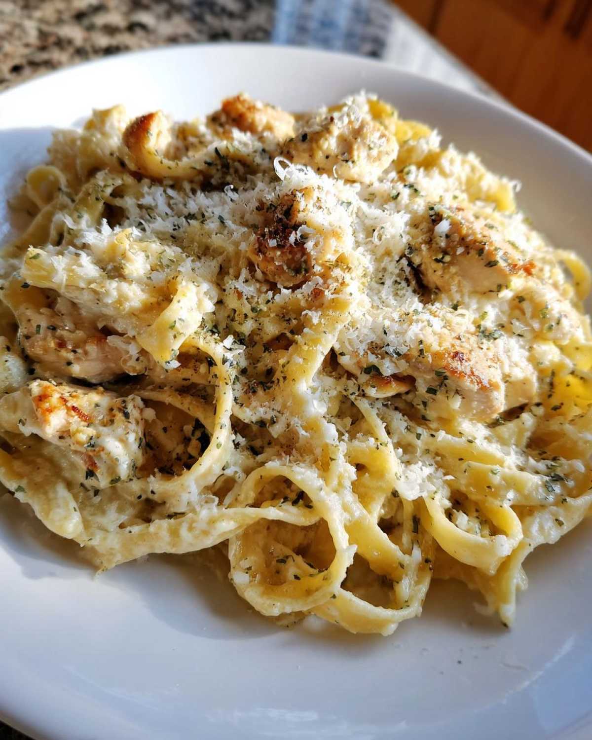 Close-up of creamy chicken fettuccine alfredo pasta topped with grated parmesan and herbs.
