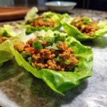 Close-up of delicious chicken lettuce wraps filled with seasoned ground chicken and topped with green onions.