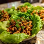 Four servings of flavorful chicken lettuce wraps filled with ground chicken mixture and topped with green onions.