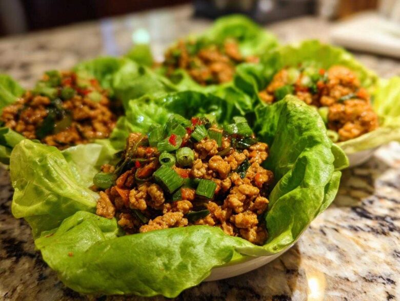 Four servings of flavorful chicken lettuce wraps filled with ground chicken mixture and topped with green onions.