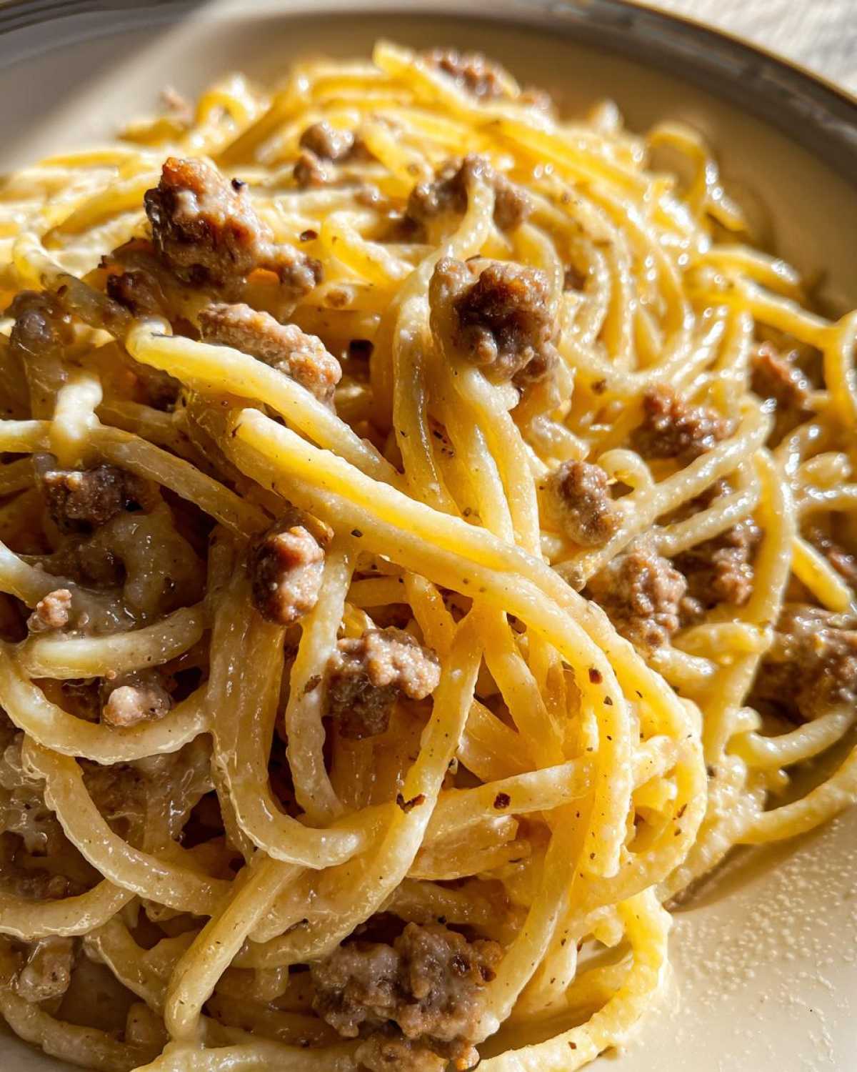 A close-up shot of spaghetti coated in a rich, creamy sauce with visible crumbles of seasoned ground beef, highlighting the creamy beef pasta.