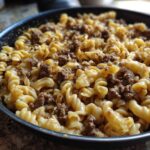 Close-up of creamy beef pasta made with fusilli noodles and ground beef sauce in a black skillet.