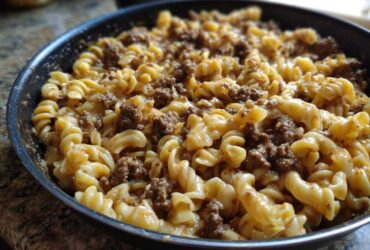 Close-up of creamy beef pasta made with fusilli noodles and ground beef sauce in a black skillet.