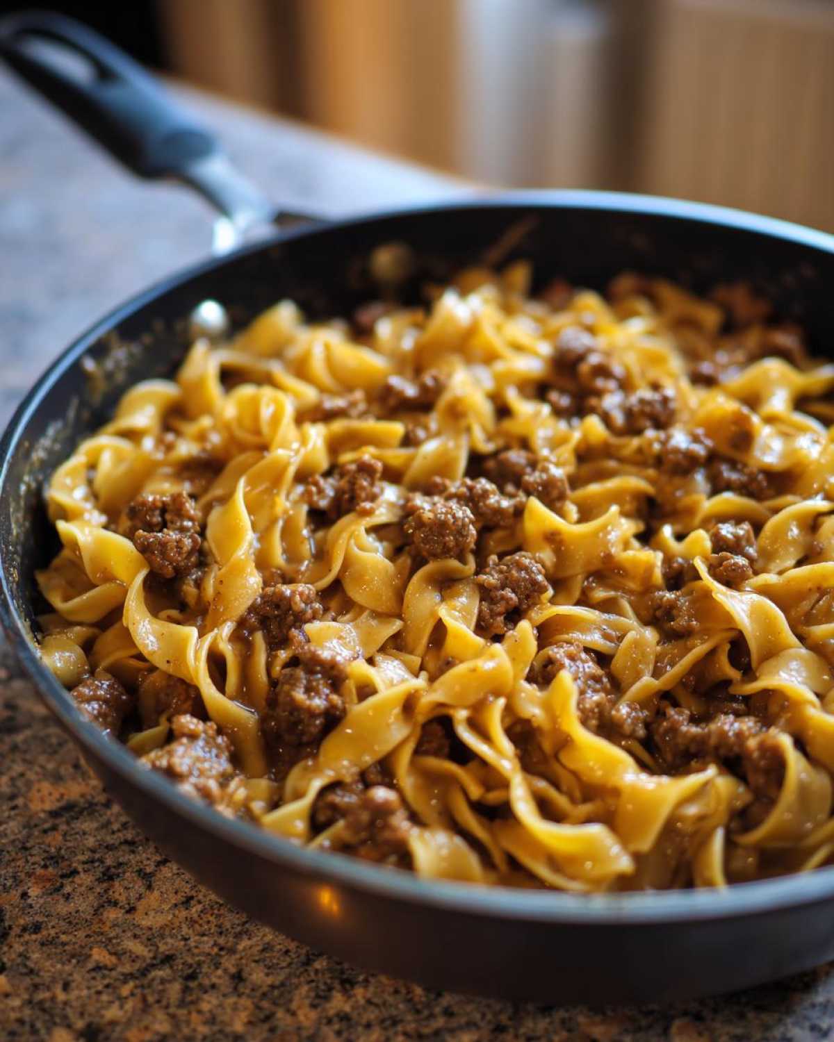 Close-up of creamy beef pasta made with egg noodles and ground beef in a black skillet.