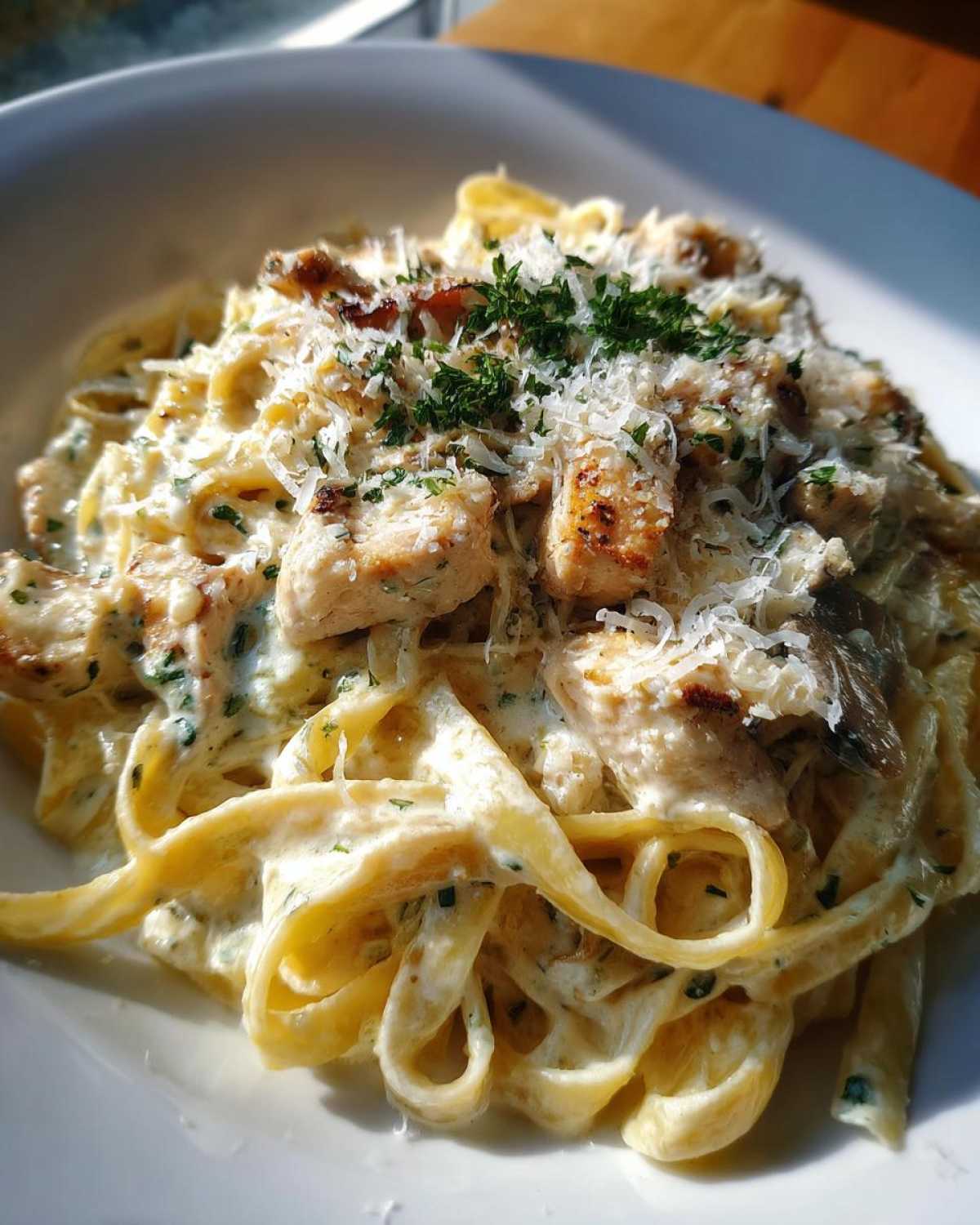 Close-up of creamy chicken fettuccine alfredo pasta topped with grated Parmesan cheese and fresh parsley.