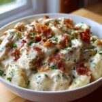A white bowl filled with creamy crack chicken gnocchi, topped with crispy bacon bits and fresh parsley.