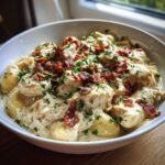 A close-up of creamy crack chicken gnocchi topped generously with crispy bacon crumbles and fresh parsley.